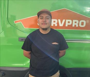 Male employee with black hair smiling in front of a green background