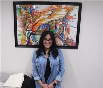 Employee standing in front of a picture frame in office. 